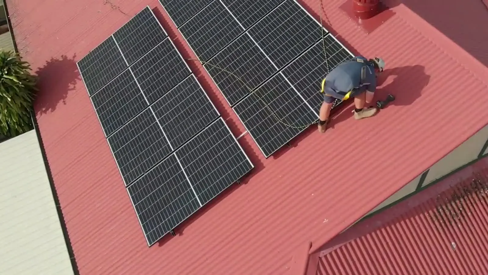 Drone view of an ABS electrician fitting solar panels on a Brisbane roof